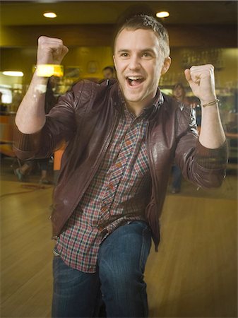 Young man with his arms raised in excitement in a bowling alley Stock Photo - Premium Royalty-Free, Code: 640-03265566