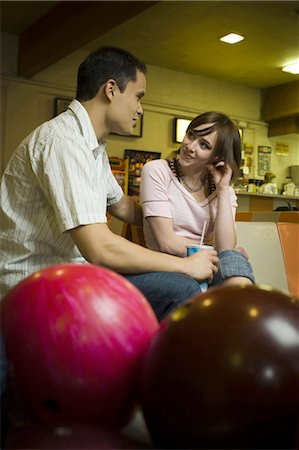 Low angle view of a young man sitting with a teenage girl in a bowling alley Stock Photo - Premium Royalty-Free, Code: 640-03265608