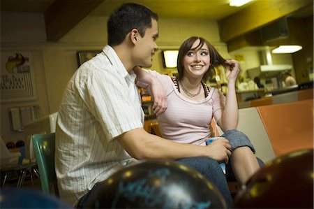 Low angle view of a young man sitting with a teenage girl in a bowling alley Foto de stock - Sin royalties Premium, Código: 640-03265609