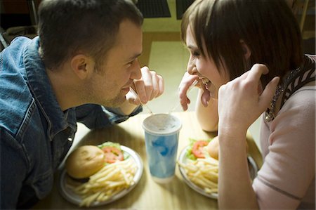 plate of hamburger and fries - High angle view of a young man and a teenage girl looking at each other and drinking Stock Photo - Premium Royalty-Free, Code: 640-03265623