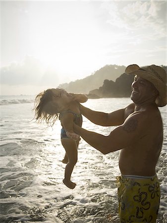 Profile of a father picking up his daughter on the beach Stock Photo - Premium Royalty-Free, Code: 640-03265649