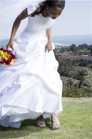 Profile of a bride holding a bouquet of flowers and looking at her shoes Stock Photo - Premium Royalty-Free, Code: 640-03265678