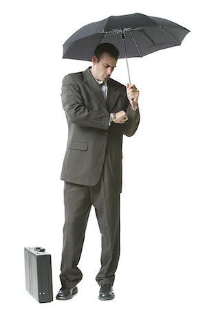 Man holding an umbrella and checking his watch Stock Photo - Premium Royalty-Free, Code: 640-03260042