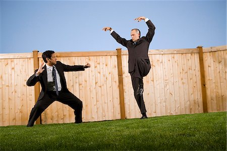 Businessmen in front of a fence playfighting Stock Photo - Premium Royalty-Free, Code: 640-03260160