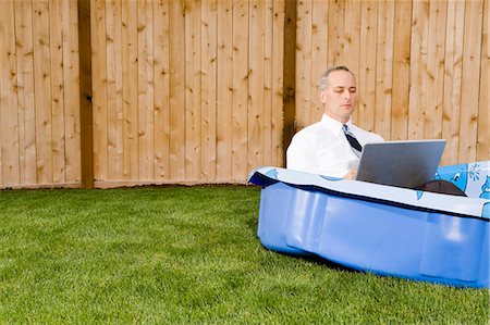 simsearch:640-03259475,k - Homme d'affaires dans une piscine d'arrière-cour sur un ordinateur portable Photographie de stock - Premium Libres de Droits, Code: 640-03260170