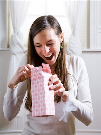 woman opening presents with a surprised look on her face Stock Photo - Premium Royalty-Free, Code: 640-03260436