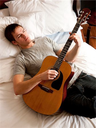 man lying in bed with his guitar Stock Photo - Premium Royalty-Free, Code: 640-03260519