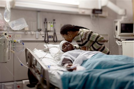 sorrow - Mother kissing boy in hospital bed with head bandages Stock Photo - Premium Royalty-Free, Code: 640-03261815