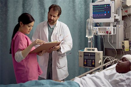 doctor patient services - Doctor looking at medical chart of boy in hospital bed Foto de stock - Sin royalties Premium, Código: 640-03261825