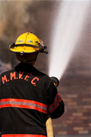 firefighter outdoors - Rear View of a firefighter with hose Foto de stock - Sin royalties Premium, Código: 640-03262198