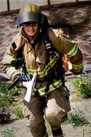 simsearch:400-06392786,k - Firefighter with axe running from blaze Fotografie stock - Premium Royalty-Free, Codice: 640-03262190