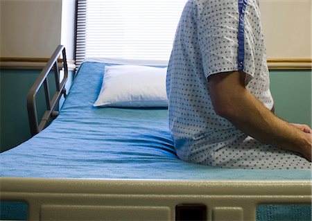 people on hospital bed - Man sitting on hospital bed in gown thinking Stock Photo - Premium Royalty-Free, Code: 640-03262510