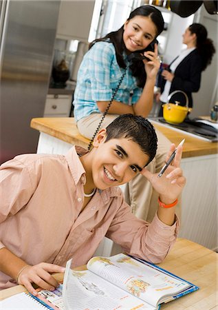 Boy studying at table with girl talking on phone Stock Photo - Premium Royalty-Free, Code: 640-03262674