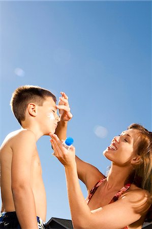 Woman applying sunscreen lotion to boy's face Stock Photo - Premium Royalty-Free, Code: 640-03262790