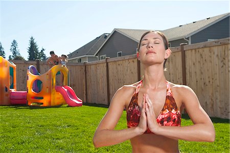 Woman doing yoga in yard with blue sky Stock Photo - Premium Royalty-Free, Code: 640-03262814