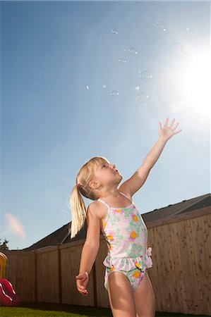 simsearch:640-03262574,k - Girl in swimsuit catching bubbles outdoors with blue sky Foto de stock - Sin royalties Premium, Código: 640-03262827