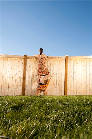 espion - Femme debout sur la chaise lorgnant sur la clôture Photographie de stock - Premium Libres de Droits, Code: 640-03262835