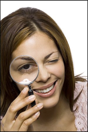 Closeup of woman holding magnifying glass to eye Fotografie stock - Premium Royalty-Free, Codice: 640-03263027