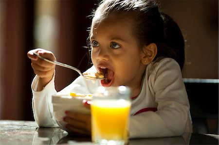 simsearch:640-03262648,k - Young girl eating cereal and glass of orange juice Stock Photo - Premium Royalty-Free, Code: 640-03263095