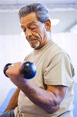 Man with one leg sitting and exercising with weights Stock Photo - Premium Royalty-Free, Code: 640-03263238