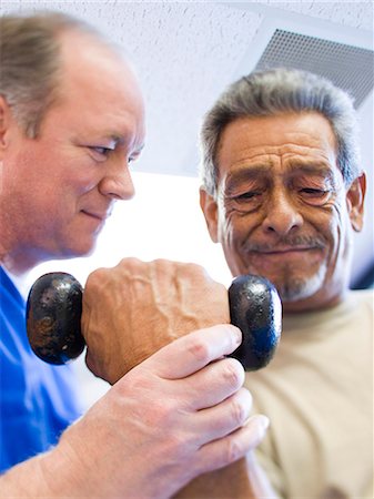 strain - Physical Therapist assisting a man with weights Stock Photo - Premium Royalty-Free, Code: 640-03263232