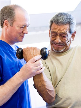 physiotherapy in older people - Physical Therapist assisting a man with weights Stock Photo - Premium Royalty-Free, Code: 640-03263233