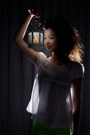 Young woman holding lamp in spot light Stock Photo - Premium Royalty-Free, Code: 642-01734007