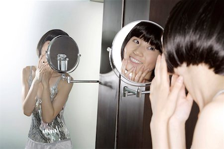 Young woman looking in mirror, smiling Stock Photo - Premium Royalty-Free, Code: 642-01734096
