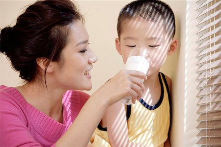 feeding asian family - Mother feeding glass of milk to son Stock Photo - Premium Royalty-Free, Code: 642-01734202