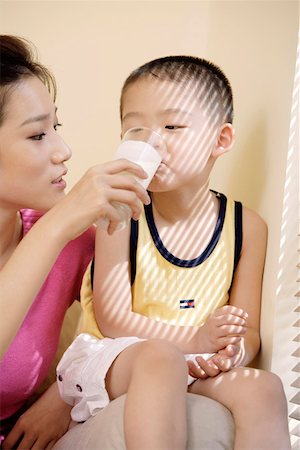 feeding asian family - Mother feeding glass of milk to son Stock Photo - Premium Royalty-Free, Code: 642-01734203