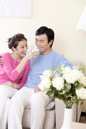 photo of a woman feeding her husband food - Wife feeding glass of milk to husband and smiling Stock Photo - Premium Royalty-Free, Code: 642-01734210
