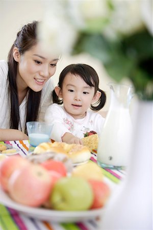 Mother and daughter with milk, fruit and bread Stock Photo - Premium Royalty-Free, Code: 642-01734253