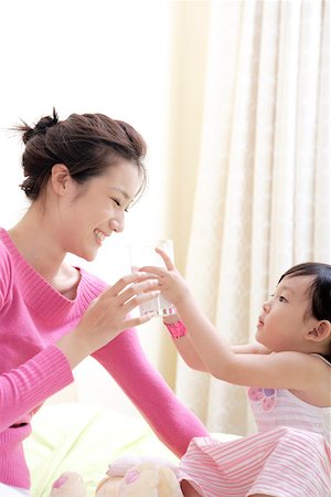 feeding asian family - Girl feeding mother with a glass of milk Stock Photo - Premium Royalty-Free, Code: 642-01734320