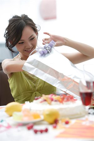 Young women opening present together, smiling Stock Photo - Premium Royalty-Free, Code: 642-01734419