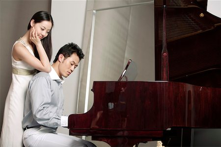 piano happy - Young man playing piano while woman standing behind him with hand on his shoulder Stock Photo - Premium Royalty-Free, Code: 642-01734507