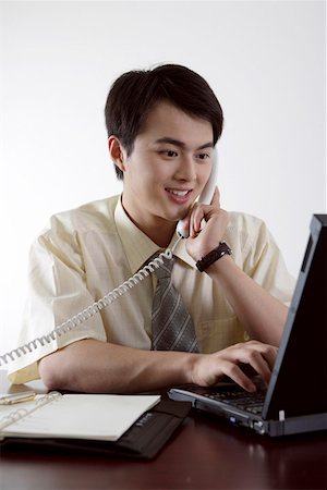 simsearch:614-02003461,k - Young businessman sitting in an office talking on the telephone and using laptop Stock Photo - Premium Royalty-Free, Code: 642-01734717