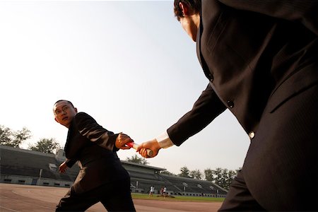 run suit low angle - Businessmen exchanging baton in a relay event Stock Photo - Premium Royalty-Free, Code: 642-01734774