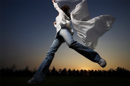 Woman jumping in air, waving white fabric , low angle view Stock Photo - Premium Royalty-Free, Code: 642-01734982