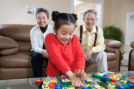 family sitting room sofa grandparents - Girl playing with alphabet blocks while grandfather and grandmother in background Stock Photo - Premium Royalty-Free, Code: 642-01735015