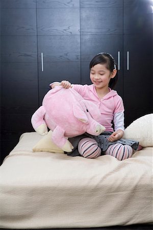simsearch:642-01735604,k - Jeune fille assise sur le lit et jouer avec des jouets, souriant Photographie de stock - Premium Libres de Droits, Code: 642-01735264