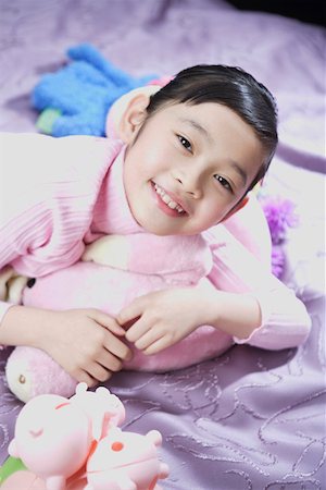 simsearch:642-01735641,k - Portrait d'une jeune fille allongée sur le lit avec des jouets Photographie de stock - Premium Libres de Droits, Code: 642-01735289