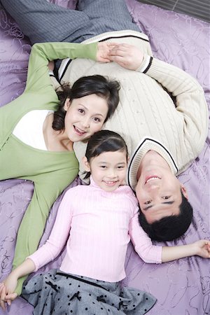 simsearch:642-01732733,k - Young couple with daughter lying on bed, smiling, overhead view Foto de stock - Royalty Free Premium, Número: 642-01735281