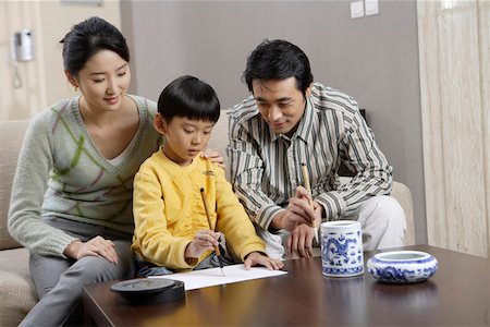 Father and Mother looking at son who practising Chinese calligraphy Stock Photo - Premium Royalty-Free, Code: 642-01735337