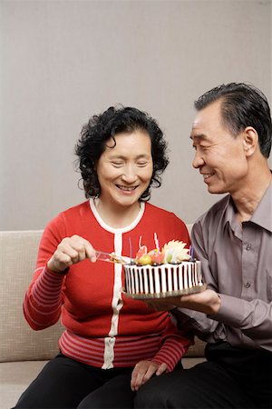 someone cutting cake - Senior man holding cake while wife cutting with knife Stock Photo - Premium Royalty-Free, Code: 642-01735349