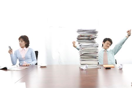 stack of phones - Woman using mobile phone while businessman stretching arms Stock Photo - Premium Royalty-Free, Code: 642-01735383