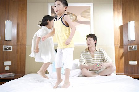 family jumping bed room - Father playing with son and daughter Stock Photo - Premium Royalty-Free, Code: 642-01735533