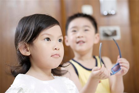 Close-up of a girl looking up while boy standing beside and holding sunglasses Stock Photo - Premium Royalty-Free, Code: 642-01735586