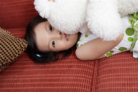 simsearch:642-01735584,k - Portrait d'une jeune fille couché sur le canapé et la tenue de jouet Photographie de stock - Premium Libres de Droits, Code: 642-01735597
