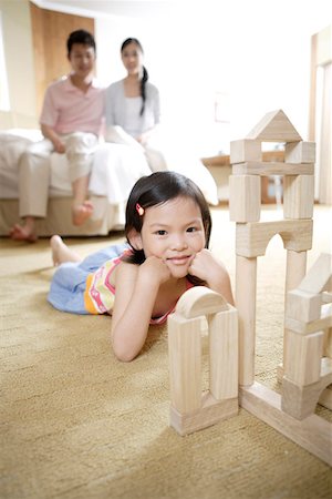 Parents watching daughter playing with building blocks on floor Stock Photo - Premium Royalty-Free, Code: 642-01735613