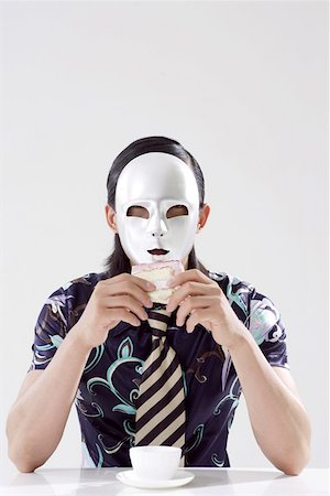 Close-up of a young man wearing mask and holding cake Stock Photo - Premium Royalty-Free, Code: 642-01735781